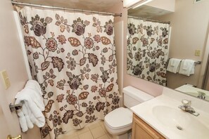 Une salle de bain avec un rideau de douche à motifs floraux, des toilettes, un lavabo et un miroir.