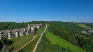 A modern hotel with multiple floors, a central courtyard, and a scenic view of a forested area. - Seven Springs Stoneridge 3 Bedroom Standard Condo, Mountain Views! by RedAwning (Champion)