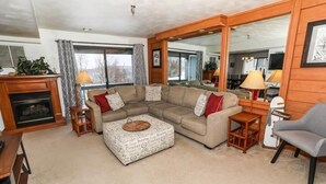 A cozy living room with a sectional sofa, a coffee table, a fireplace, and a large mirror. - Seven Springs Stoneridge 3 Bedroom Standard Condo, Mountain Views! by RedAwning (Champion)