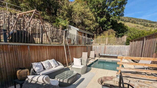 A backyard with a pool, wicker furniture, and a wooden fence. - Le Cottage ****, 4-bedroom house in the heart of the historic center of Kaysersberg, with parking facilities. (Kaysersberg-Vignoble)