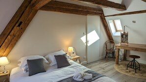 A cozy, well-lit bedroom with a large bed, a desk, and a chair. - Le Cottage ****, 4-bedroom house in the heart of the historic center of Kaysersberg, with parking facilities. (Kaysersberg-Vignoble)
