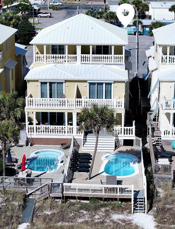 Ein Hotel mit zwei Etagen und einem Poolbereich, inklusive eines kleinen Pools und eines größeren Pools mit Liegestühlen.