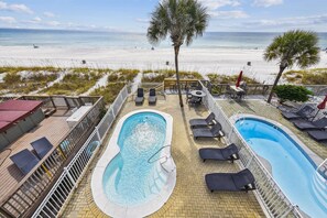Ein Poolbereich mit zwei Pools, Liegestühlen und Blick auf den Strand.