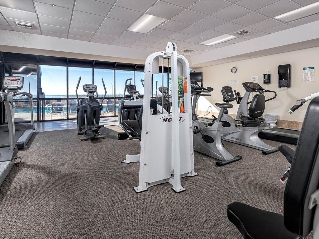 Ein Fitnessraum mit Cardiogeräten, Krafttrainingsgeräten und einem großen Fenster mit Blick ins Freie.