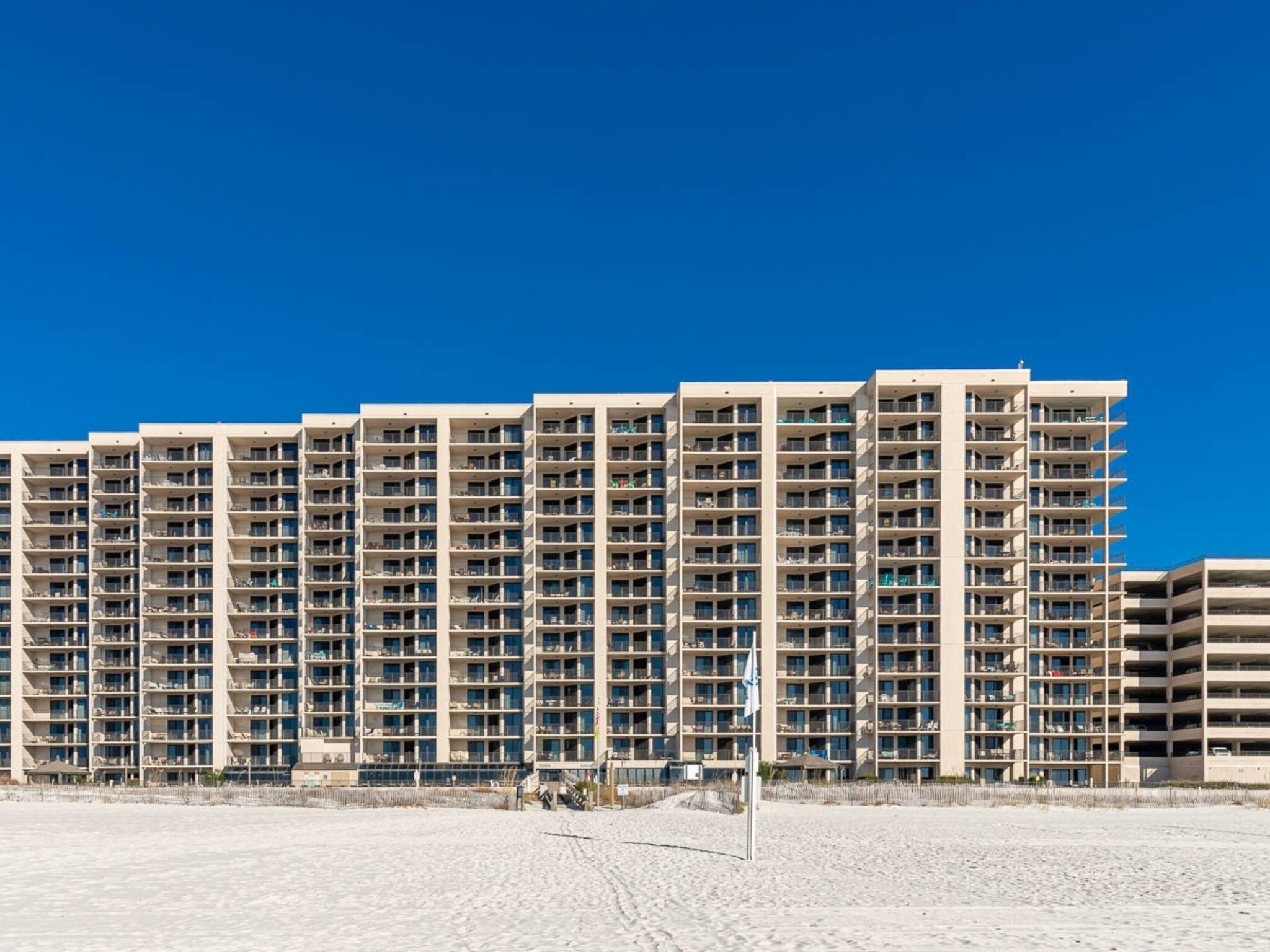 A high-rise hotel with multiple floors, balconies, and a beach view.