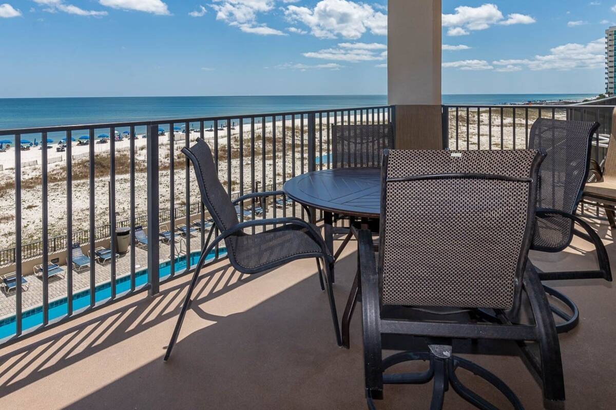 Ein Balkon mit Blick auf den Strand, ein Pool und ein Tisch mit Stühlen.