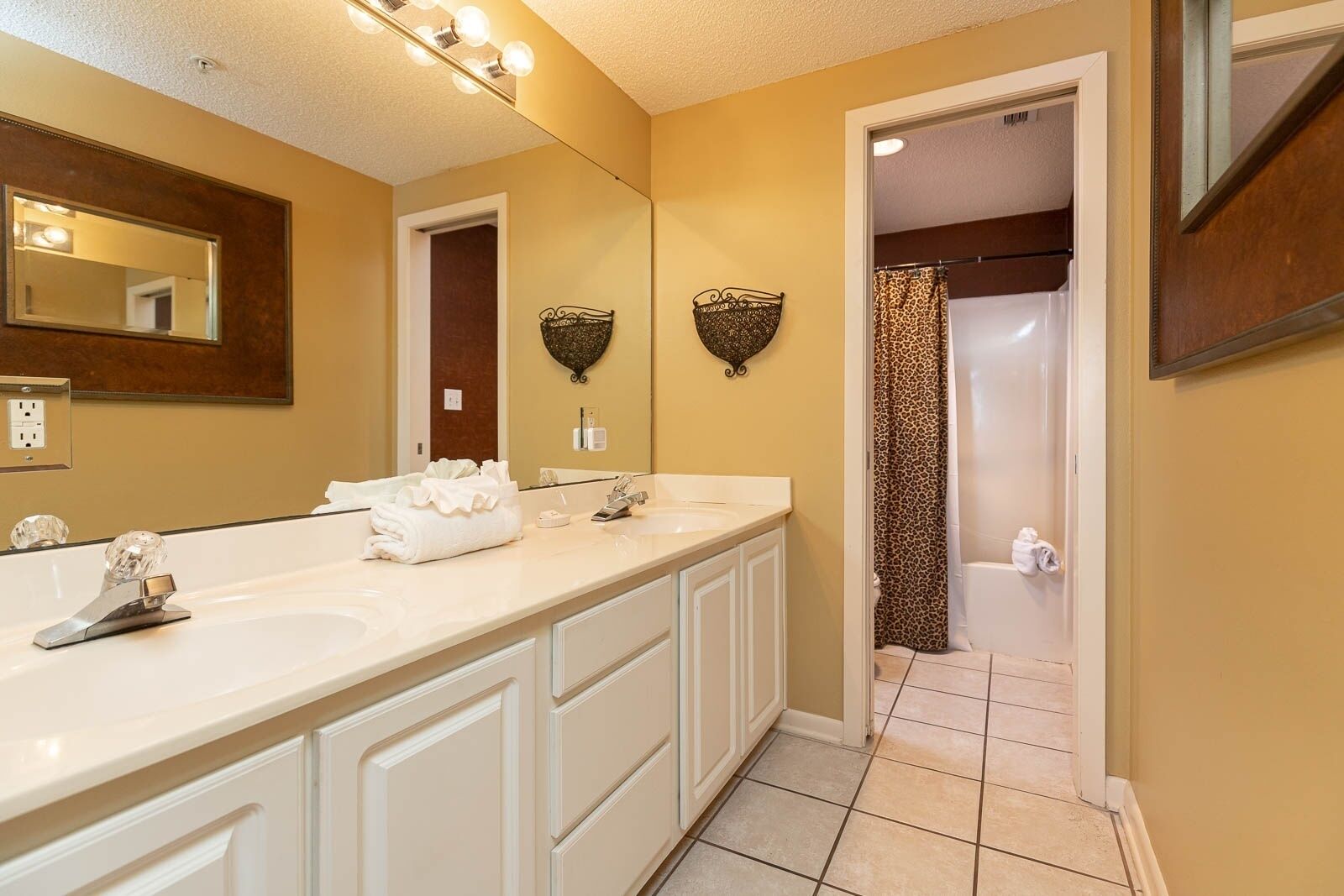 A bathroom with two sinks, a large mirror, and a shower with a leopard print curtain.