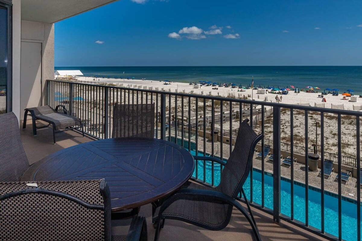 Ein Balkon mit Blick auf den Strand, ein Pool und Sitzgelegenheiten im Freien.