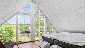 Camera da letto moderna tipo loft con un'ampia vetrata sul tetto, un letto, una sedia e contenitori portaoggetti.