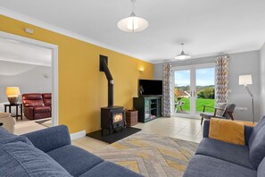 Un salon avec un canapé, une cheminée, un téléviseur et une vue sur l’extérieur.