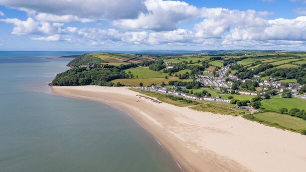 A coastal town with a sandy beach, rolling green hills, and a castle in the distance. - A Family Home Near Estuary & Llansteffan Castle (Llansteffan)