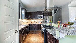 A modern kitchen with dark cabinets, stainless steel appliances, and a granite countertop. -  Stay in Style Where the Musicians Live 6-beds, 4-bedroom, 3-bath   (Nashville)