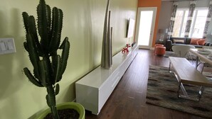 A modern living room with a green potted cactus, a white cabinet, and a wooden dining table. -  Stay in Style Where the Musicians Live 6-beds, 4-bedroom, 3-bath   (Nashville)