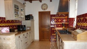 Une cuisine dotée d’un plan de travail en pierre, de meubles en bois, d’un four à micro-ondes et d’un crédence carrelée.
