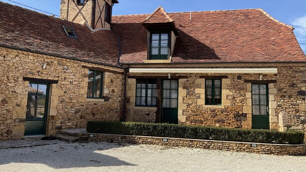 Un bâtiment en pierre avec un toit recouvert de tuiles rouges, de nombreuses fenêtres et une petite tour.