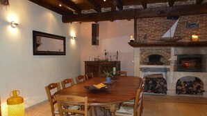 Un coin repas avec une table et des chaises en bois, une plante en pot et une cheminée.