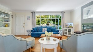 Ein Wohnzimmer mit einem blauen Sofa, zwei Sesseln, einem Couchtisch und einem Fernseher.
