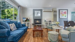 Ein Wohnzimmer mit einem blauen Sofa, einem Couchtisch, einem Kamin und einem Fernseher.