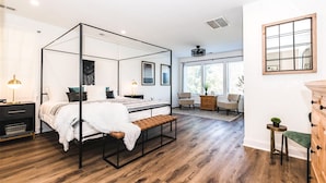 Une chambre à coucher moderne avec un lit à baldaquin, un plancher en bois, un petit bureau et une chaise.