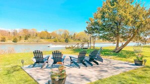 Une terrasse avec des fauteuils Adirondack et une plante en pot.