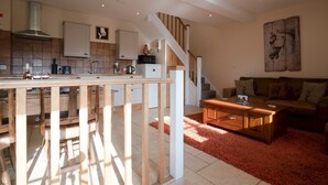 A spacious living area with a wooden coffee table, a sofa, and a kitchen area with a stove and cabinets.