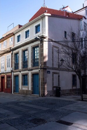 A traditional building with a stone and plaster exterior, featuring a blue door and metal grille.