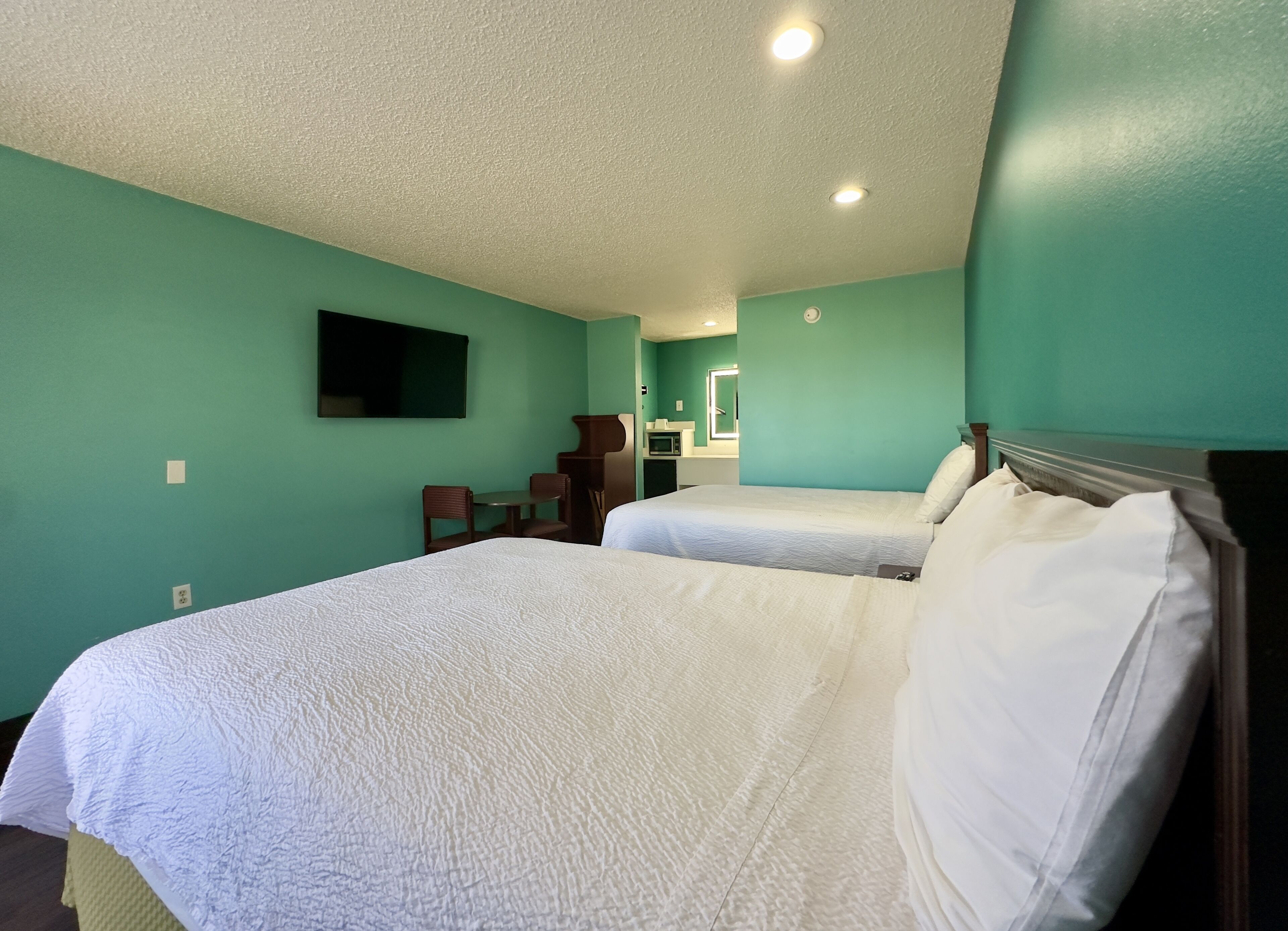Habitación de hotel con dos camas, una mesita y una silla.