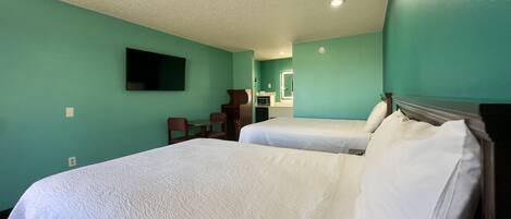 Habitación de hotel con dos camas, una mesita y una silla.