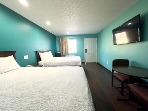A hotel room with two beds, a desk, a chair, a television, and a door. - Razorback Inn (Rogers)