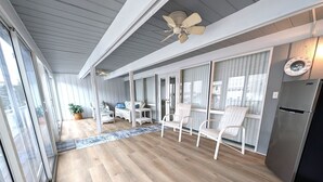 Une cuisine moderne dotée d’un réfrigérateur en acier inoxydable, d’un plancher en bois et d’un ventilateur de plafond.