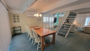 Un vaste espace dédié à la salle à manger, avec une table et des chaises en bois, un escalier et une vue sur le salon.