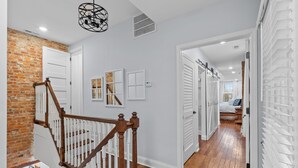 A staircase with wooden railings leading to a room with a brick wall and white doors.