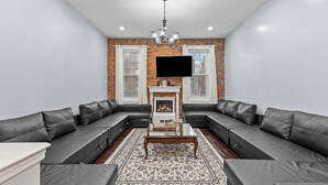 A modern living room with a sectional sofa, a fireplace, and a flat-screen TV.