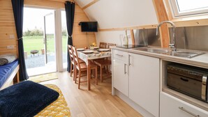 Ett mysigt och kompakt kök med träbjälkar, en matplats med bord och stolar samt ett stort fönster.