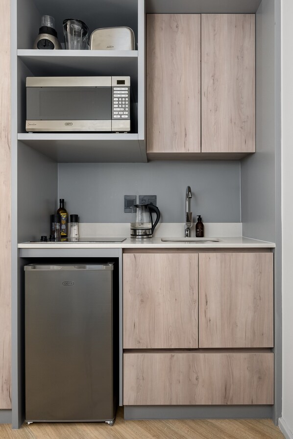 Una cocina compacta con microondas integrado, cafetera y lavabo.