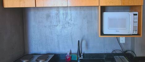 Una cocina con armarios de madera, microondas, estufa y refrigerador.