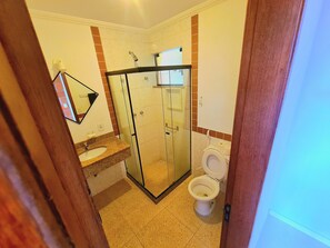 A bathroom with a glass-enclosed shower, a sink, and a toilet. - Varandas ao Mar (Arraial do Cabo)