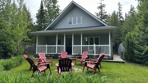 A two-story house with a porch and six Adirondack chairs. - Cottage in the heart of Tobermory - AC & WIFI (Tobermory)