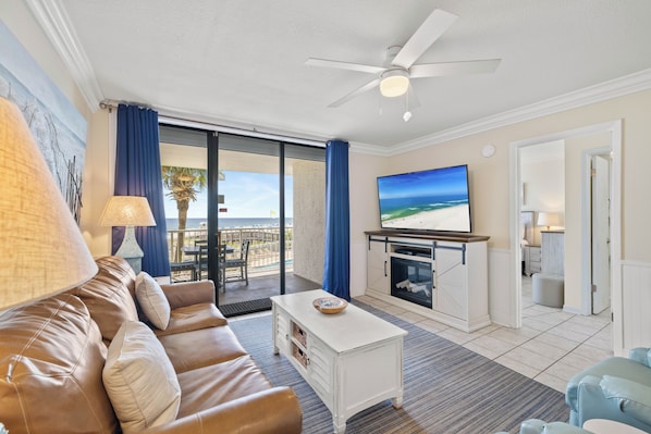 A living room with a sofa, a coffee table, a flat-screen TV, and a ceiling fan.