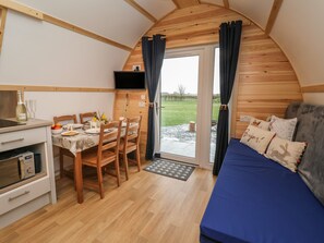 A cozy, wooden interior with a dining area, a kitchenette, and a bed with a view.