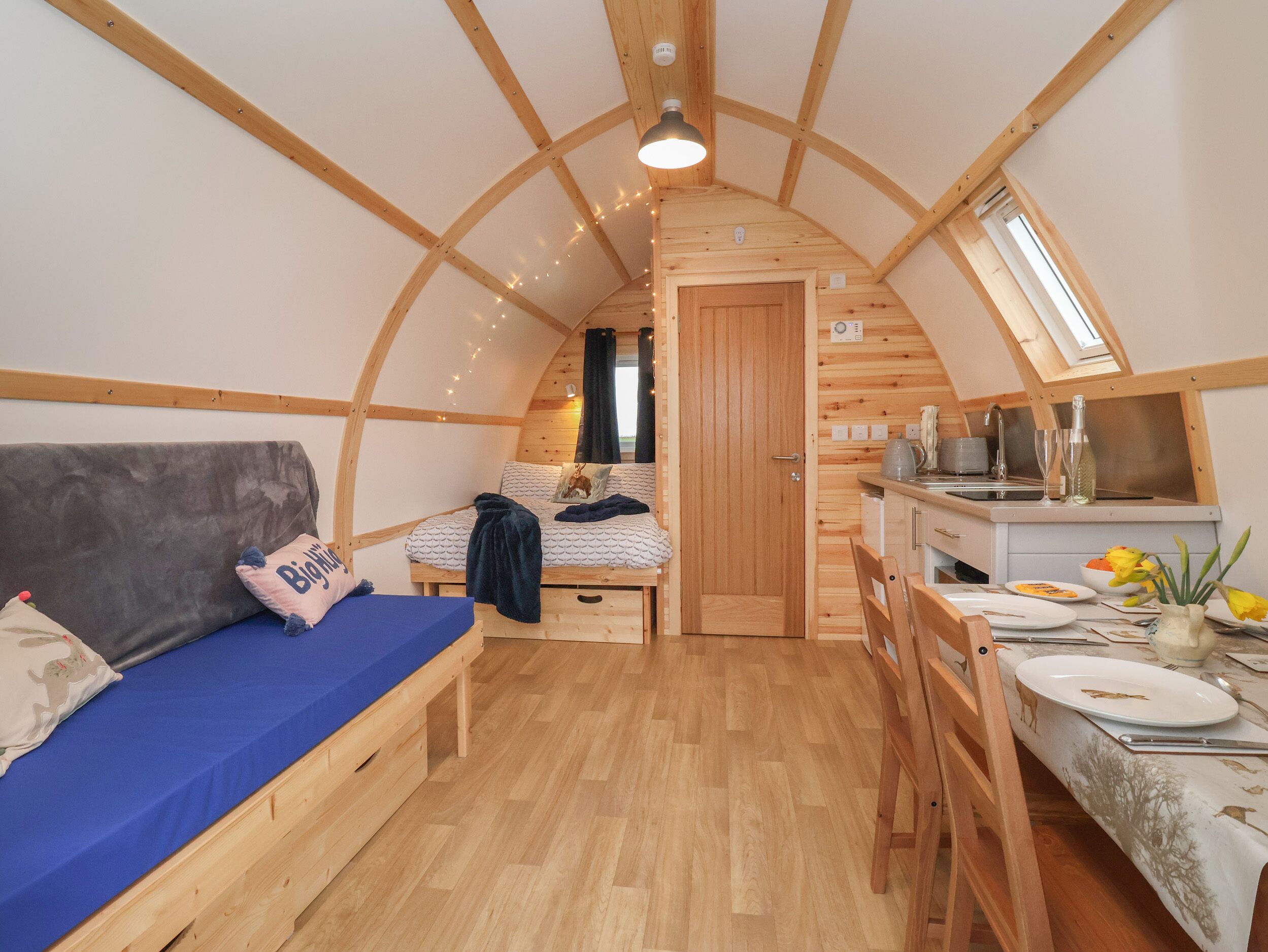 A cozy, compact room with a bed, a small table, and a kitchenette.