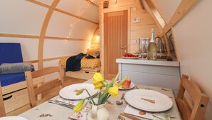 Un'atmosfera accogliente con un tavolo da pranzo in legno apparecchiato per due persone, un letto con testiera blu e un angolo cottura.