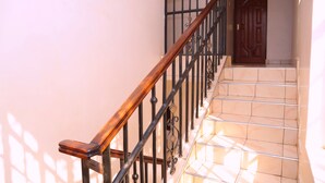 Una escalera con barandillas de madera y balaustradas de metal negro que lleva a una puerta con el número 8.