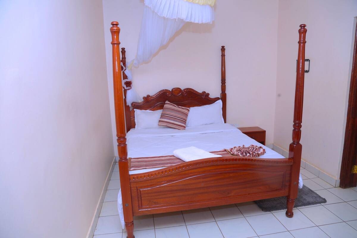 A four-poster bed with a wooden headboard, white bedding, and striped pillows.