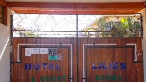 Una verja de madera con carteles que indican 'HOTEL & GUEST ROOMS' y 'LILIES ROOMS'.