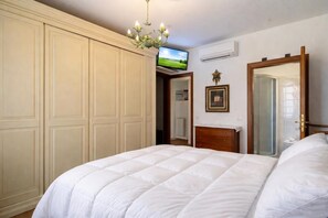 Une chambre à coucher avec un lit, une armoire, une télévision et un miroir.