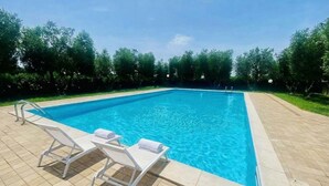 Une piscine rectangulaire à l’eau d’un bleu limpide, entourée d’une terrasse carrelée.