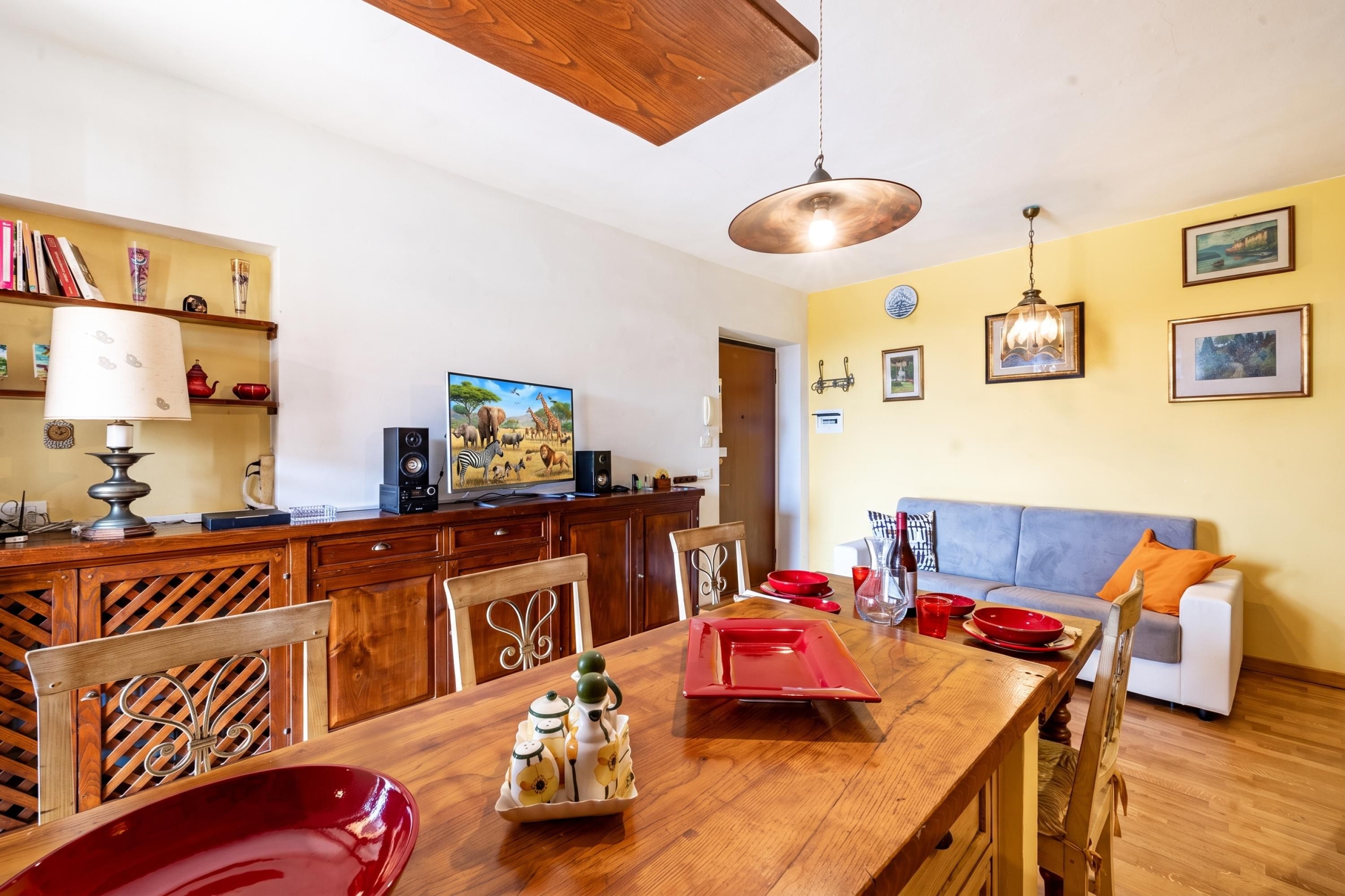 Ein Essbereich mit Holztisch, Stühlen, einem Fernseher und einer Couch.
