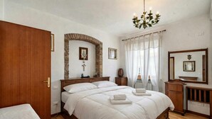 Une chambre à coucher avec un lit en bois, une arche en pierre, un lustre et un miroir.