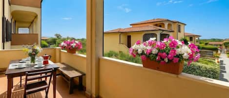 A balcony with a table set for two, a chair, and a flower pot.